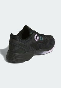 Černá sportovní bota s síťovaným svrškem a gumovou podrážkou, barevnými špunty a výrazným designem pro styl a oporu.