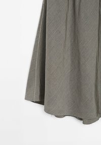 Harmaa hame, joka on valmistettu tekstuurista kankaasta ja jossa on timanttikuvio hienoilla viivoilla. Helma on hieman frayed, mikä lisää yksityiskohtia muotoiluun.