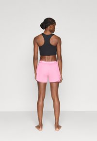 Μαύρο αθλητικό κοντό τοπ και ροζ πλισέ σορτς με πλαϊνή τσέπη, με λογότυπο στη ζώνη. Απλός σχεδιασμός, απαλή υφή.