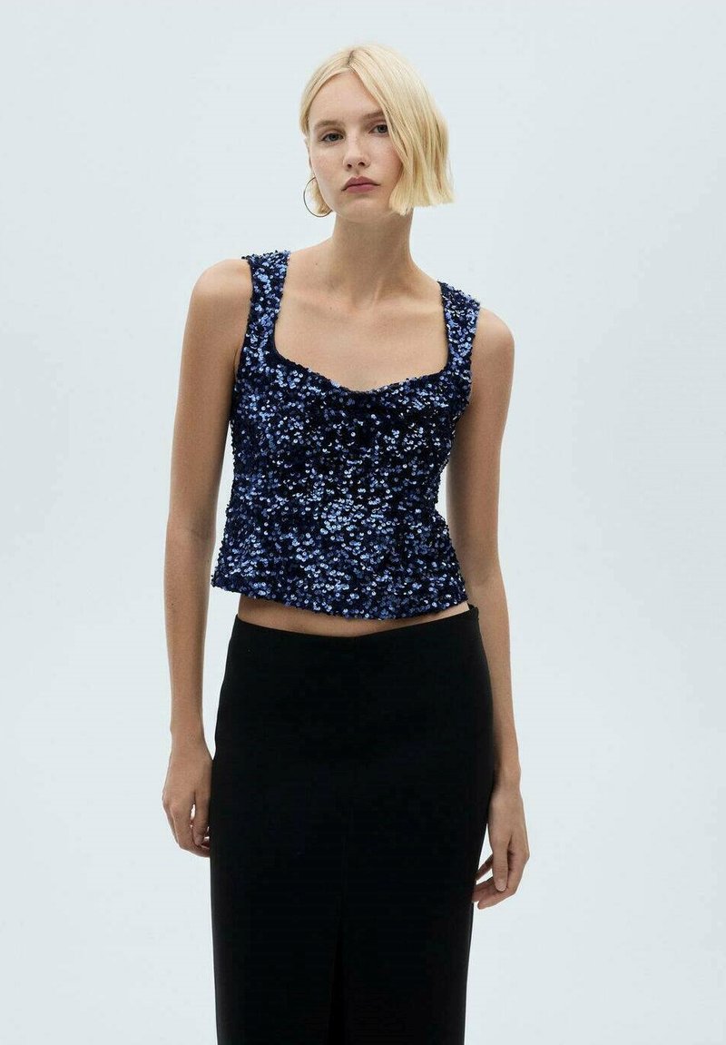 Námornícky modrý crop top so flitrami a štvorcovým výstrihom, s ramienkami, v kombinácii s čiernou sukňou s vysokým pásom a predným rozparkom.
