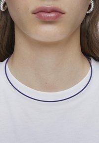 T-shirt bianco in cotone con collo rotondo aderente e bordino viola. Tessuto corto e liscio, texture minima e senza motivi visibili.