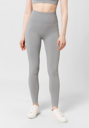 Grijze geribde legging met een hoge tailleband, met een gladde textuur en een strak aansluitend ontwerp. Gecombineerd met witte sneakers.