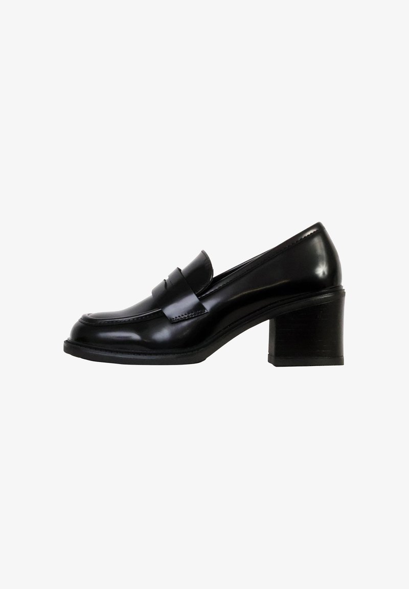 Mocassins à talons en cuir noir avec un bout arrondi et une sangle décorative à l'avant, présentant un talon texturé et une finition lisse.