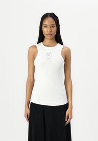 Weißes geripptes Tanktop mit rundem Halsausschnitt und breiten Schulterträgern, mit einem kleinen Drucketikett auf der Vorderseite. Glatte Textur.