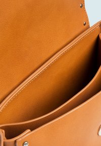 Interno di borsa in pelle marrone con due scomparti spaziosi, texture liscia e dettaglio di cuciture a contrasto. Chiusura a cerniera metallica.