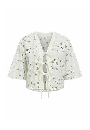 Cardigan court blanc avec motifs floraux découpés, manches courtes et trois attaches nouées à l'avant.