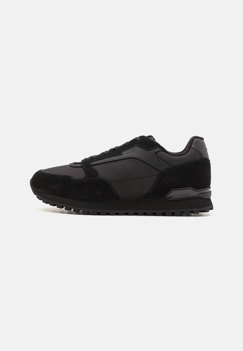 Zapatillas negras con una mezcla de nylon liso y ante texturizado. Presentan una suela de goma gruesa y acentos en contraste.