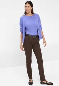 Pull en maille côtelée violet clair, cardigan léger avec des boutons, pantalon ajusté marron et ballerines en mesh noires. Design simple et structuré.