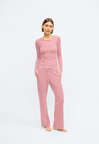 Μπλούζα με μακριά μανίκια σε κόκκινο και λευκό ριγέ σχέδιο, με στρογγυλή λαιμόκοψη, συνδυασμένη με αντίστοιχο άνετο χαλαρό παντελόνι που έχει ρυθμιζόμενη μέση με κορδόνι.