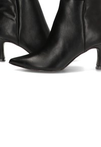 Botas de cuero negras hasta el tobillo con punteras afiladas y tacones delgados de altura media, mostradas sobre un fondo blanco.
