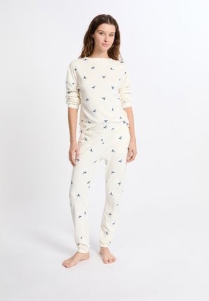 Set di pigiama crema composto da una maglia a maniche lunghe e pantaloni, decorato con piccoli motivi a fiocco blu, realizzato in un morbido tessuto con una vestibilità rilassata.
