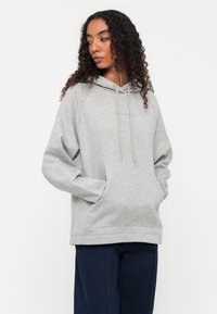Grijze hoodie met een voorzak, raglanmouwen en trekkoordjes; gemaakt van zachte stof en heeft een relaxte pasvorm.