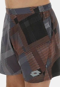 Shorts de sport pour homme avec un motif géométrique en noir, gris et orange, présentant un petit logo blanc sur le bas de la jambe.