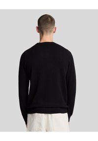 Schwarzer Rundhalsausschnitt-Pullover aus weichem Stoff, mit langen Ärmeln, gestreiften Bündchen und geradem Saum. Die Rückansicht zeigt ein glattes, minimalistisches Design.