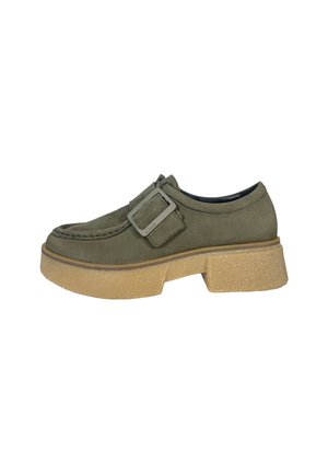 Green suede shoe with a rounded toe, buckle accent, and a chunky beige sole. Features textured upper and contrasting stitching details.