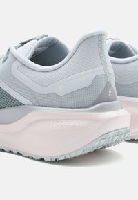 Zapatillas de correr en gris y verde menta con una parte superior de malla texturizada, marca GORE-TEX, y una suela acolchada rosa que presenta patrones de tracción.