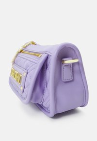 Fialová kožená kabelka s prošívaným vzorem, zlatými doplňky, přední kapsou a zakřiveným tvarem. Disponuje zipem a dekorativním popruhem.