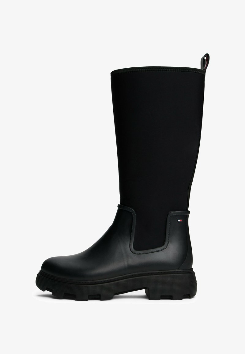 Black waterproof knee-high boot made of rubber and textile, featuring a textured sole, curved top, and accent logo detail.