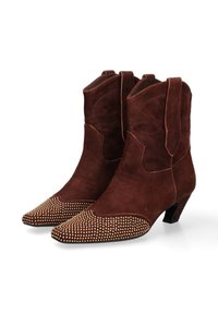Stivali da cowboy in suede marrone con punta a punta, caratterizzati da accenti borchiati sulla punta e cuciture decorative lungo il gambo. Tacco basso a blocco.
