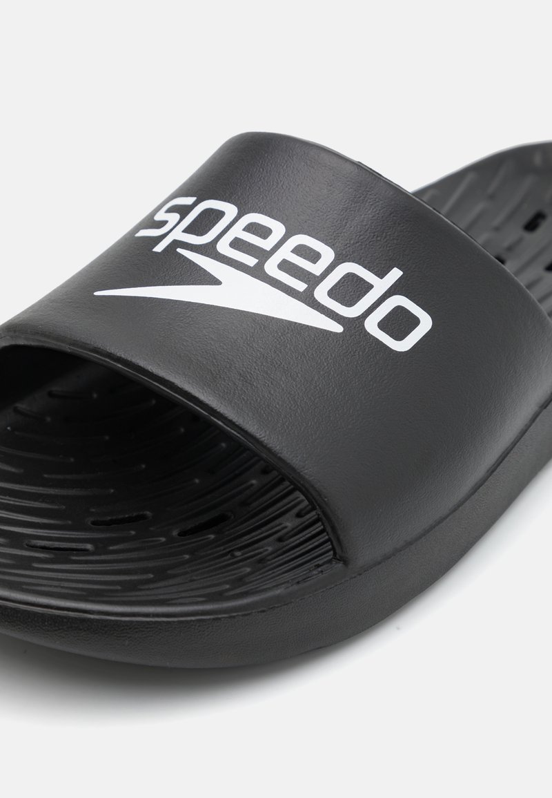 Czarne klapki z szerokim paskiem, na którym znajduje się białe logo Speedo. Teksturowana wkładka z otworami odpływowymi zapewnia wentylację. Wytrzymały materiał.