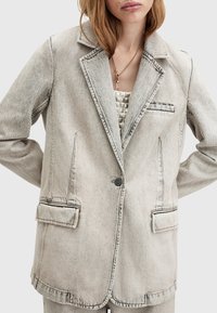 Blazer in denim grigio sbiadito con silhouette sartoriale, revers a notched, chiusura con un bottone e tasche frontali. Tessuto texture con leggero effetto invecchiato.