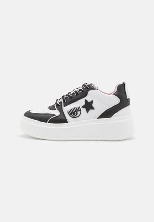 Sneakers platform in bianco e nero con design grafici di occhi e stelle, pelle testurizzata e suola in gomma bianca, dotati di lacci neri e interno rosa.