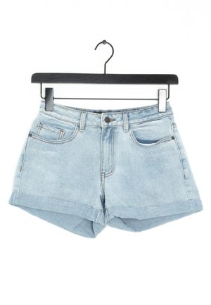 Pantalones cortos de mezclilla azul claro con dobladillo enrollado, que cuentan con dos bolsillos frontales y pasadores para cinturón. El material es suave y tiene una textura desgastada.