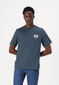 Short-sleeve crew neck t-shirt in dark blue cotton with a small white graphic design on the left chest and a straight fit.