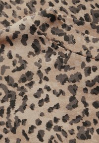 Tejido con estampado de leopardo que presenta un fondo beige con manchas irregulares en negro y marrón oscuro. Textura suave, material ligero.