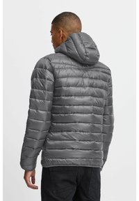 Grå puffjakke med horisontal quiltet design, med hette, elastiske mansjetter og glatt, blank tekstur. Ingen synlige lukkinger.