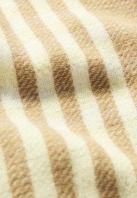 Katoenen stof met een abstract patroon van afwisselende beige en crème strepen, met een gestructureerde, geweven uitstraling.