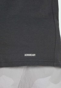 Mørkegrå sportstrøje lavet af åndbart stof, med ribbede teksturer og et hvidt "AEROREADY" logo nær kanten.