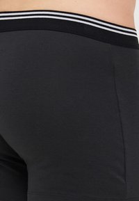 Black cotton blend boxer shorts featuring a stretchy waistband with white and grey stripes. Smooth texture, designed for comfort and fit.