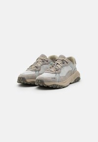 Sneakers grigio chiaro con accenti beige, materiali in rete e suede, punta arrotondata, suola testurizzata con modelli di trazione e design con stringhe.