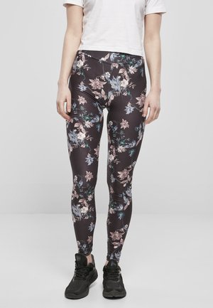 Sorte blomsterleggings med en gloss overflate, med et flerfarget blomsterdesign. Kombinert med sorte joggesko.