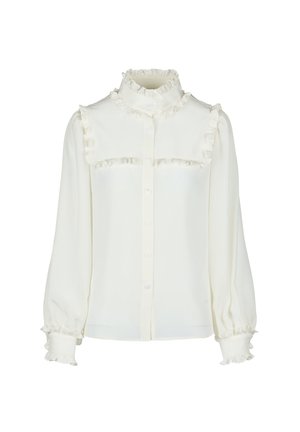 White blouse with a high frilled collar, button closure, and frill accents along the chest and sleeves. Soft, textured fabric.