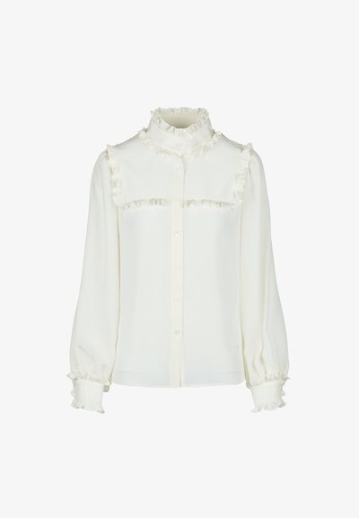 Blusa bianca con colletti arricciati alti, chiusura con bottoni e dettagli arricciati lungo il petto e le maniche. Tessuto morbido e testurizzato.