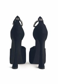 Decolletè platform neri in suede con punta affusolata, alto tacco a stiletto e decorazioni sulle cinghie alla caviglia. Texture liscia e design elegante.