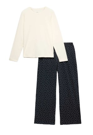 Wit topje met lange mouwen gecombineerd met zwarte wijde broek met wit polkadotpatroon.