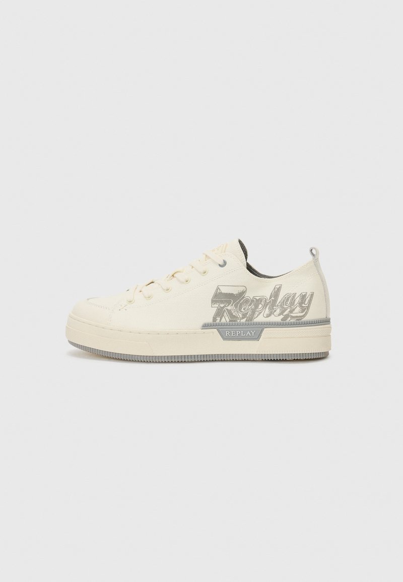 Light beige canvas sneaker with a rubber sole, featuring a grey embroidered logo on the side and a reinforced toe cap.