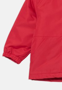 Rote Jacke mit elastischen Bündchen, glatter Textur und abgerundetem Saum. Keine sichtbaren Beschläge oder Muster; zeichnet sich durch ein einfaches, modernes Design aus.
