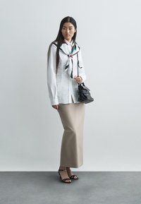 White button-up shirt, beige pencil skirt, black heeled sandals, and a small black handbag. Scarf tied at the neck with color accents.