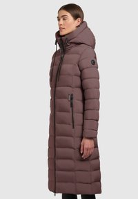 Lang dunjakke i mauve, med vandrette quiltede sektioner, en stor hætte og sorte lynlåsdetaljer. Materialet er glat og polstret.