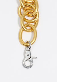 Cadena de metal dorado con grandes eslabones redondeados, con un clip de metal plateado brillante en el extremo. Textura suave con un acabado pulido.