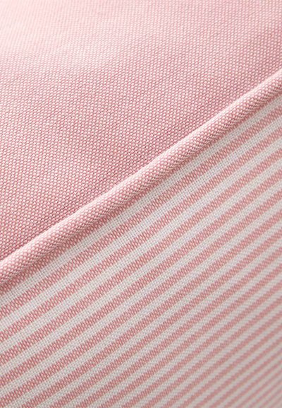 Κοντινό πλάνο ροζ υφάσματος με υφαντή υφή στην κορυφή και ροζ-άσπρο ριγέ μοτίβο από κάτω, διαχωρισμένα με στρογγυλεμένη ραφή.