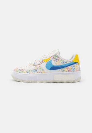 Low-top white sneaker with colorful floral patterns, blue Nike swoosh, yellow heel tab, and white sole with textured grip.