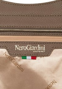 Interno in pelle marrone con texture e cerniera dorata, con etichette "NeroGiardini" e "Made in Italy". Piccolo dettaglio con la bandiera italiana visibile.