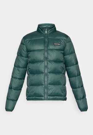 Chaqueta acolchada verde con cremallera frontal completa, cuello alto, bolsillos laterales con cremallera y parche del logo de Calvin Klein en el pecho.