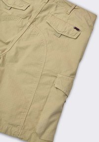 Pantaloni cargo beige con molteplici tasche, una trama morbida e un tessuto leggero con un leggero motivo a griglia.