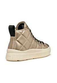 Zapatilla alta en dorado metálico con textura acolchada, cordones negros y suela de goma crema. Cuenta con una lengüeta en el talón.